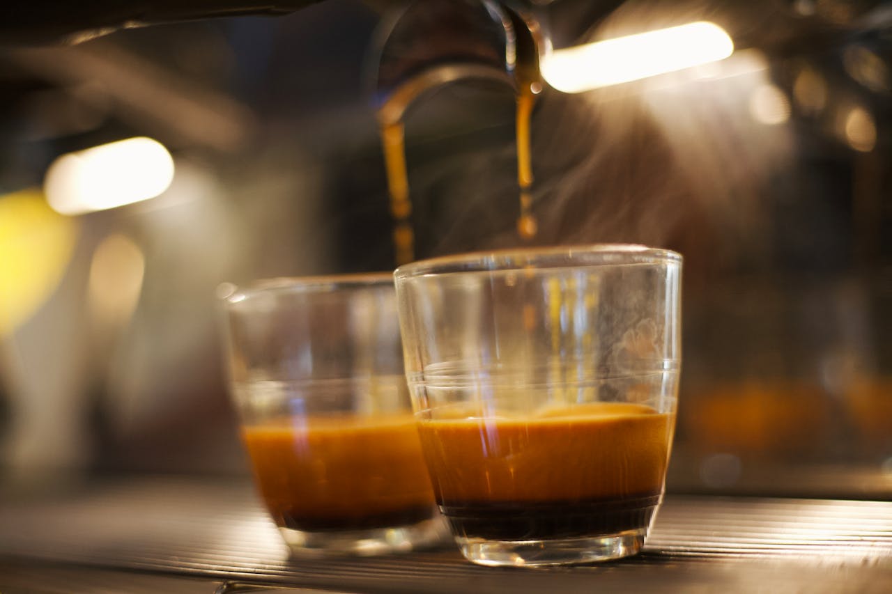 why-choose-us Close-up of espresso shot brewing in clear glass, showcasing coffee richness and steam.